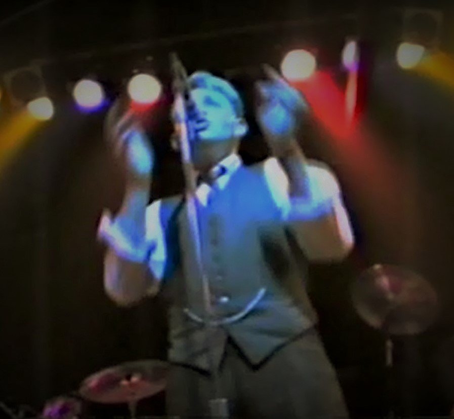 Reid Basso singing at the Cactus Club in San Jose beneath blue, red and amber stage lights