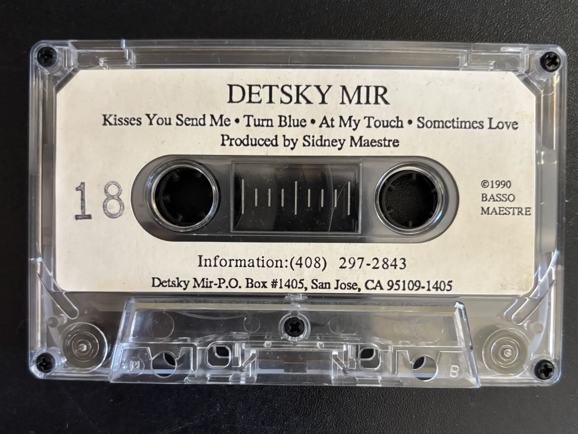 Clear cassette tape with a cream Detsky Mir four-song demo label, photographed against a black surface