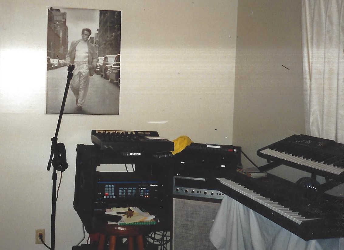 1989 colour snapshot of a bedroom studio corner with a synthesizer rack, two keyboards, a microphone stand and a film poster on the wall